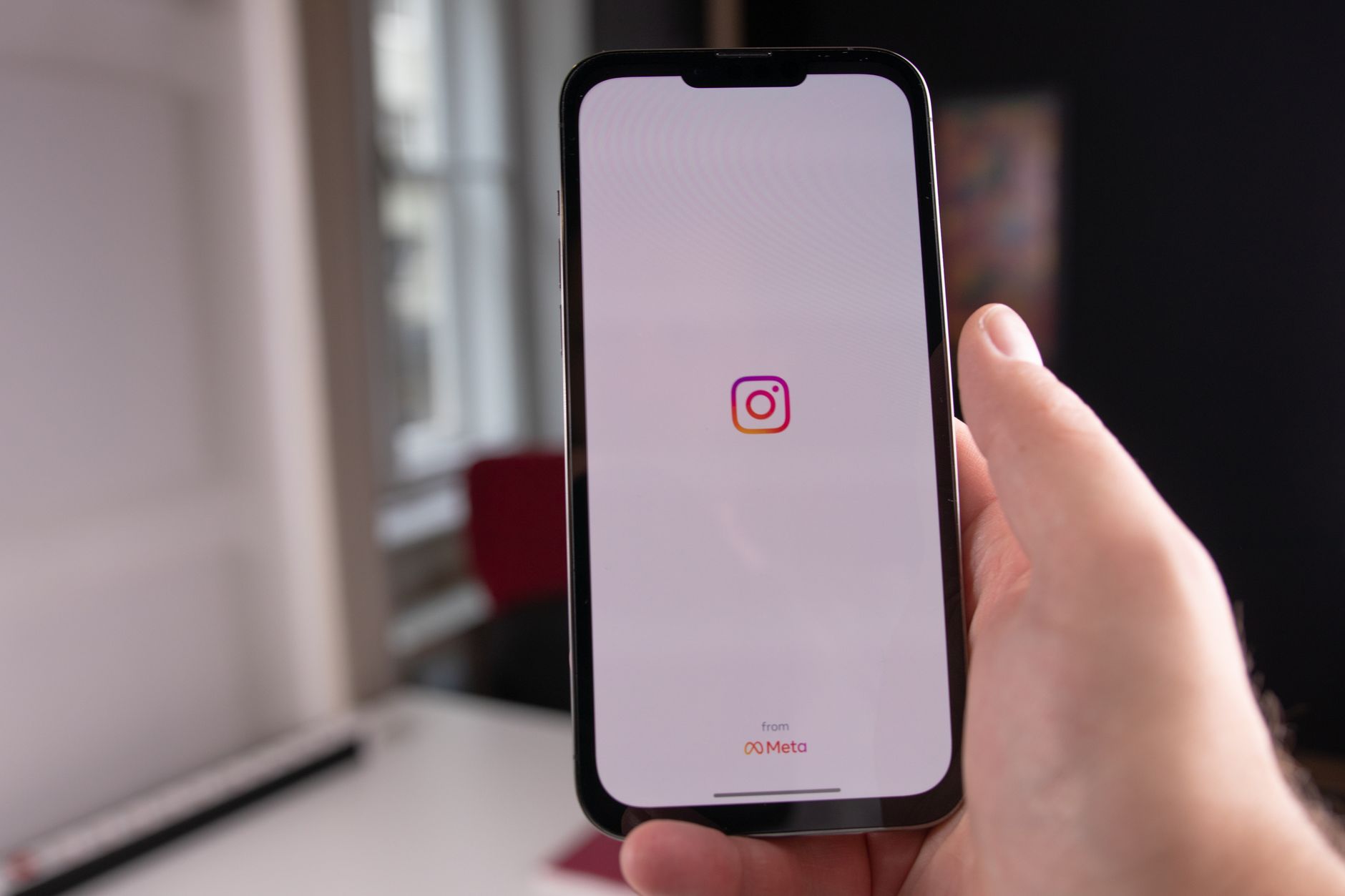 Close-up of a hand holding a smartphone showing the Instagram app opening screen