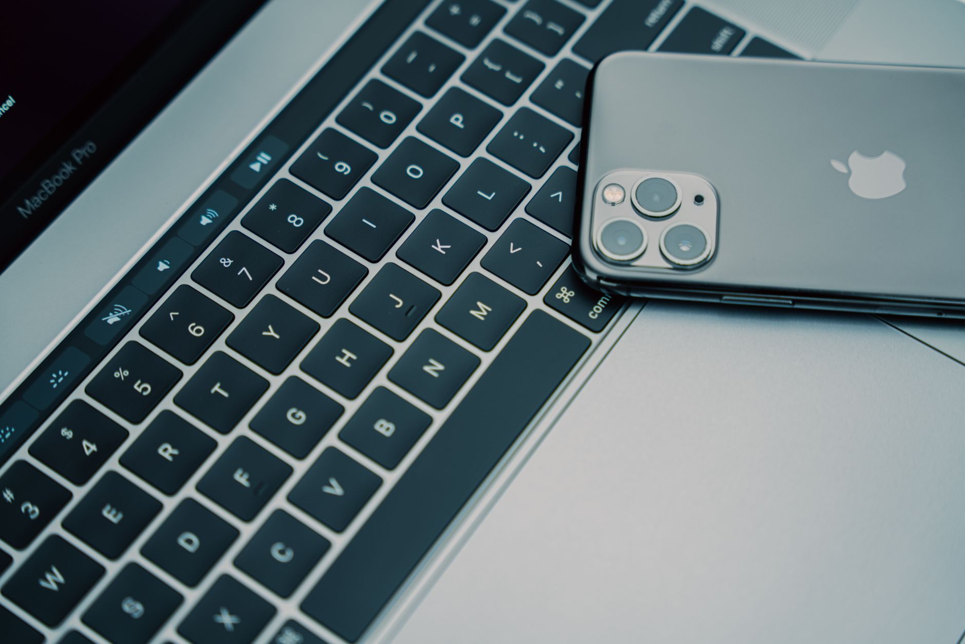 A smartphone resting on the keyboard of a MacBook Pro laptop.