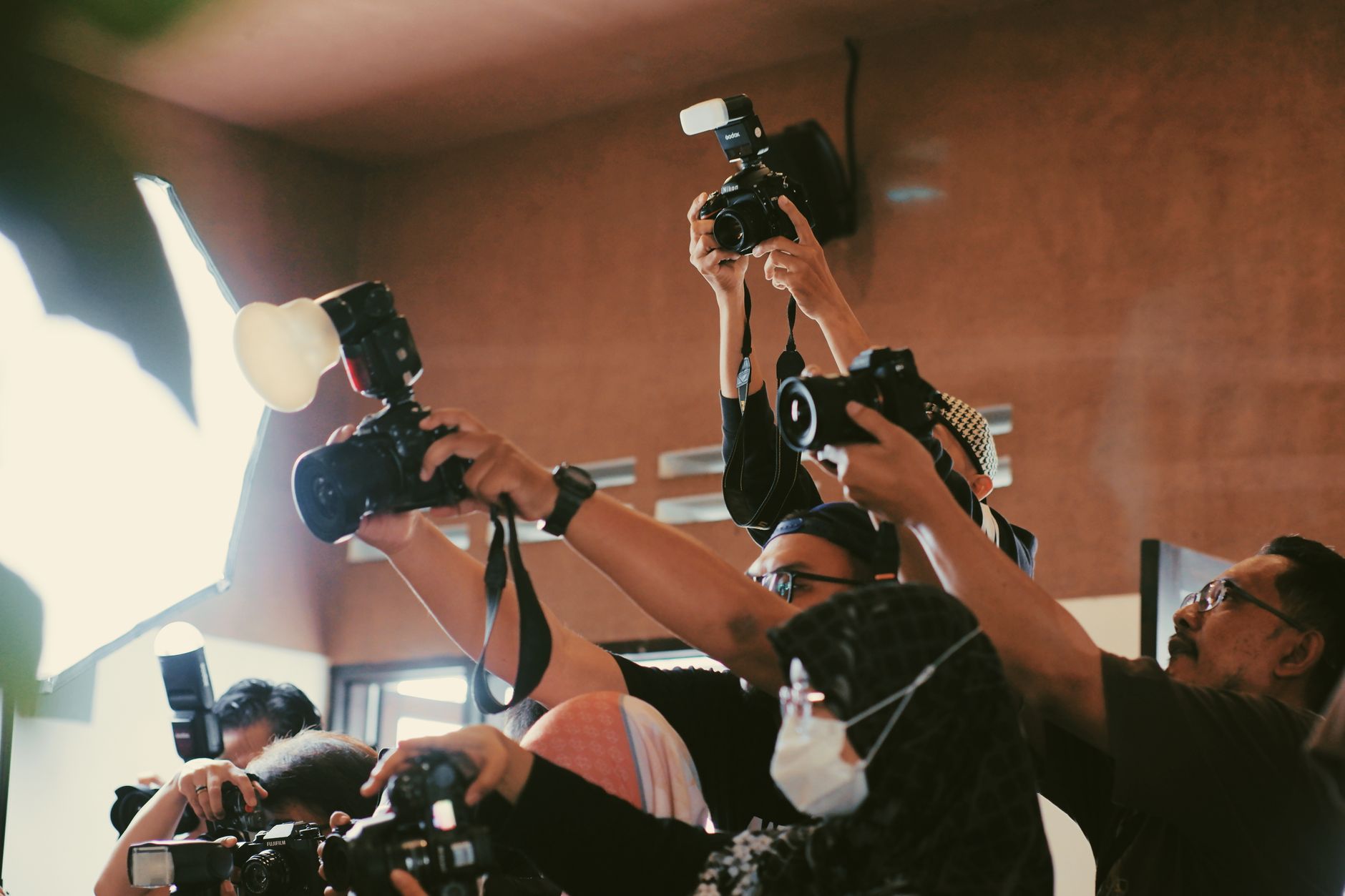 A group of photographers holding cameras up over a crowd to capture an event.
