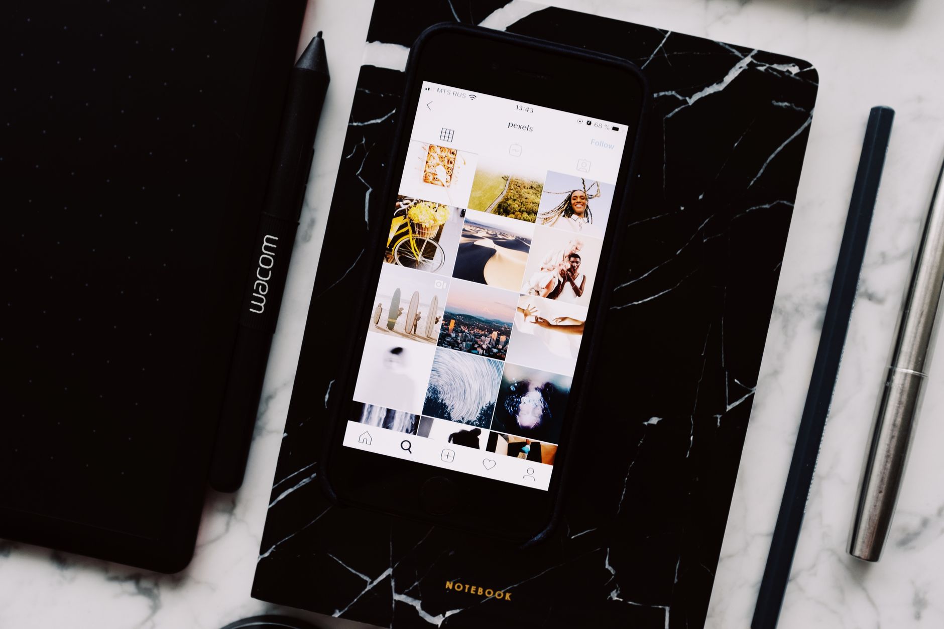 Smartphone showing an Instagram photo grid resting on a notebook