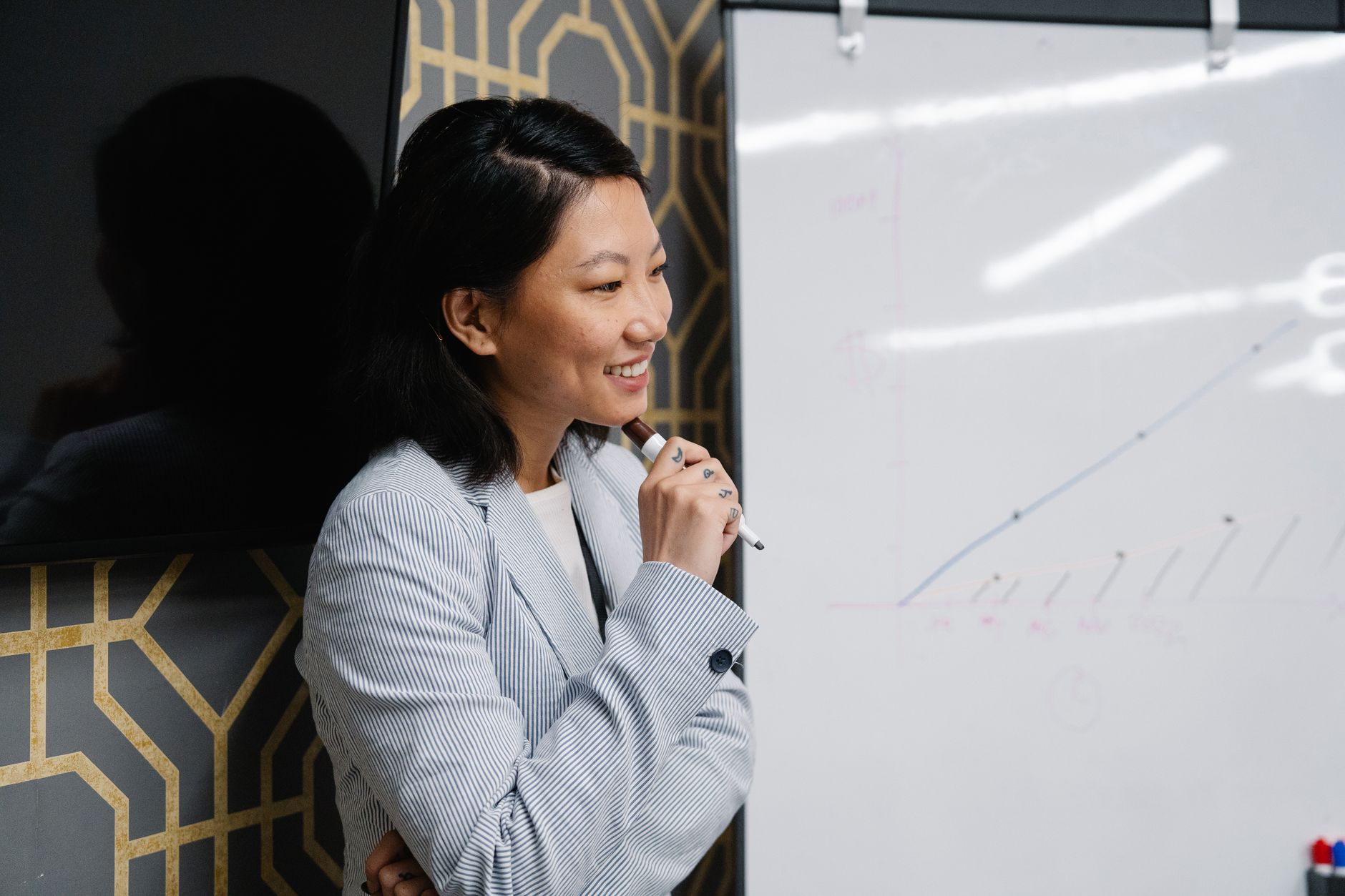 Smiling businesswoman holding a marker beside a whiteboard easel showing a hand drawn growth chart