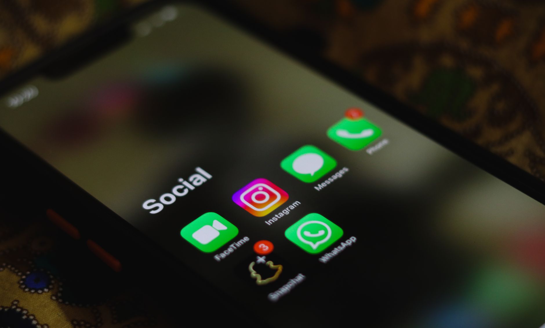 Close up of a smartphone screen showing the Instagram app icon inside a folder with other social apps