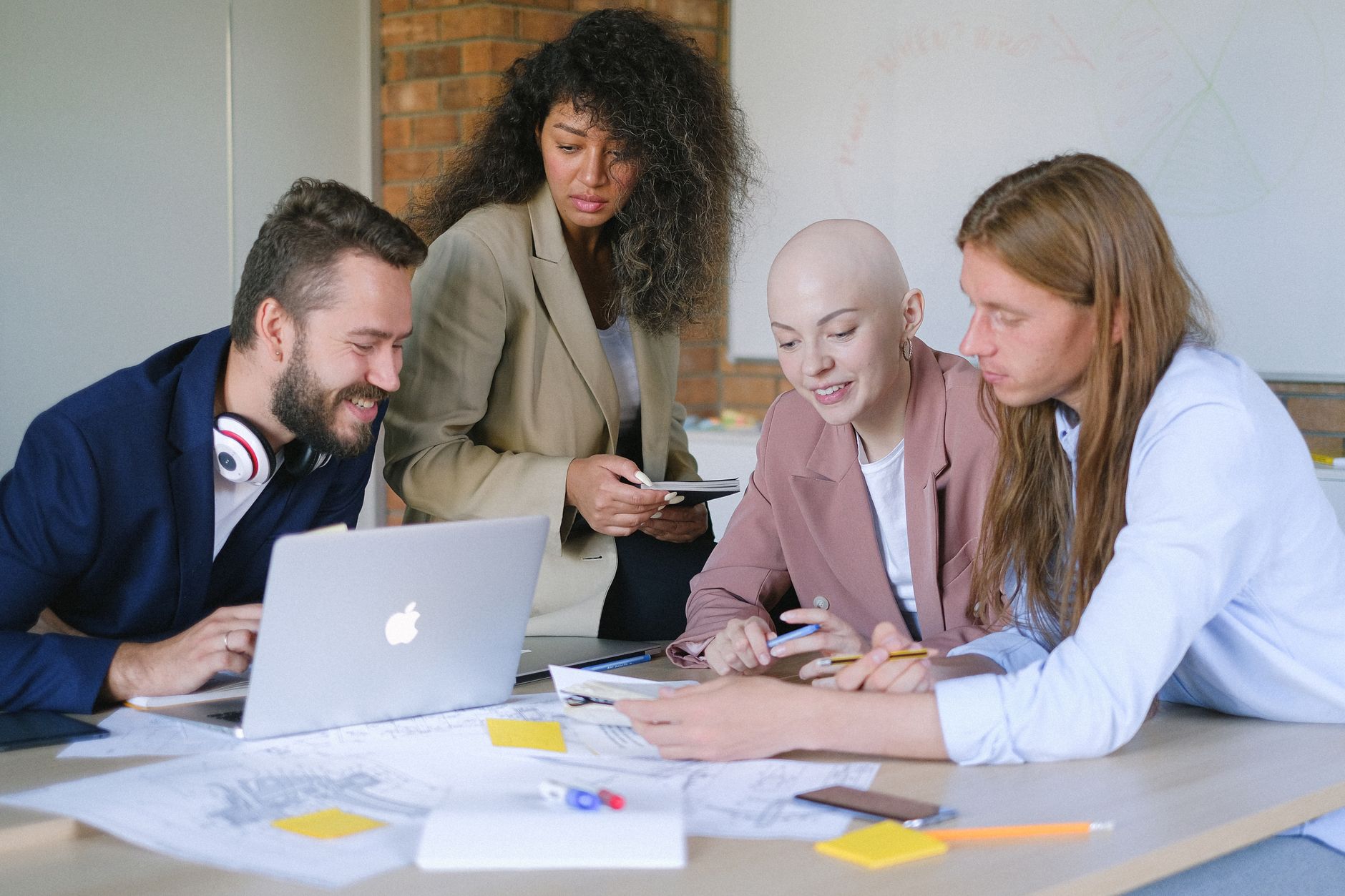 Multiethnic colleagues talking and reviewing papers together around a laptop at a table