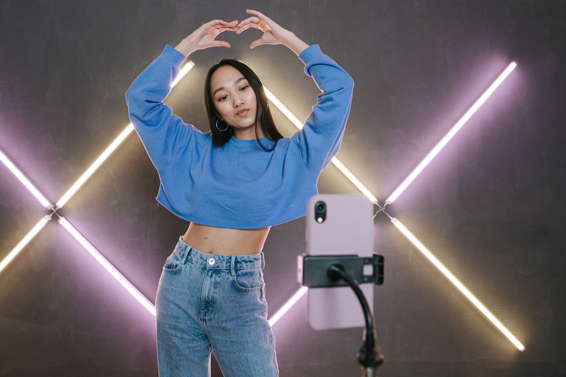 Fashionable young woman posing for a mobile shoot with ring lights in a studio