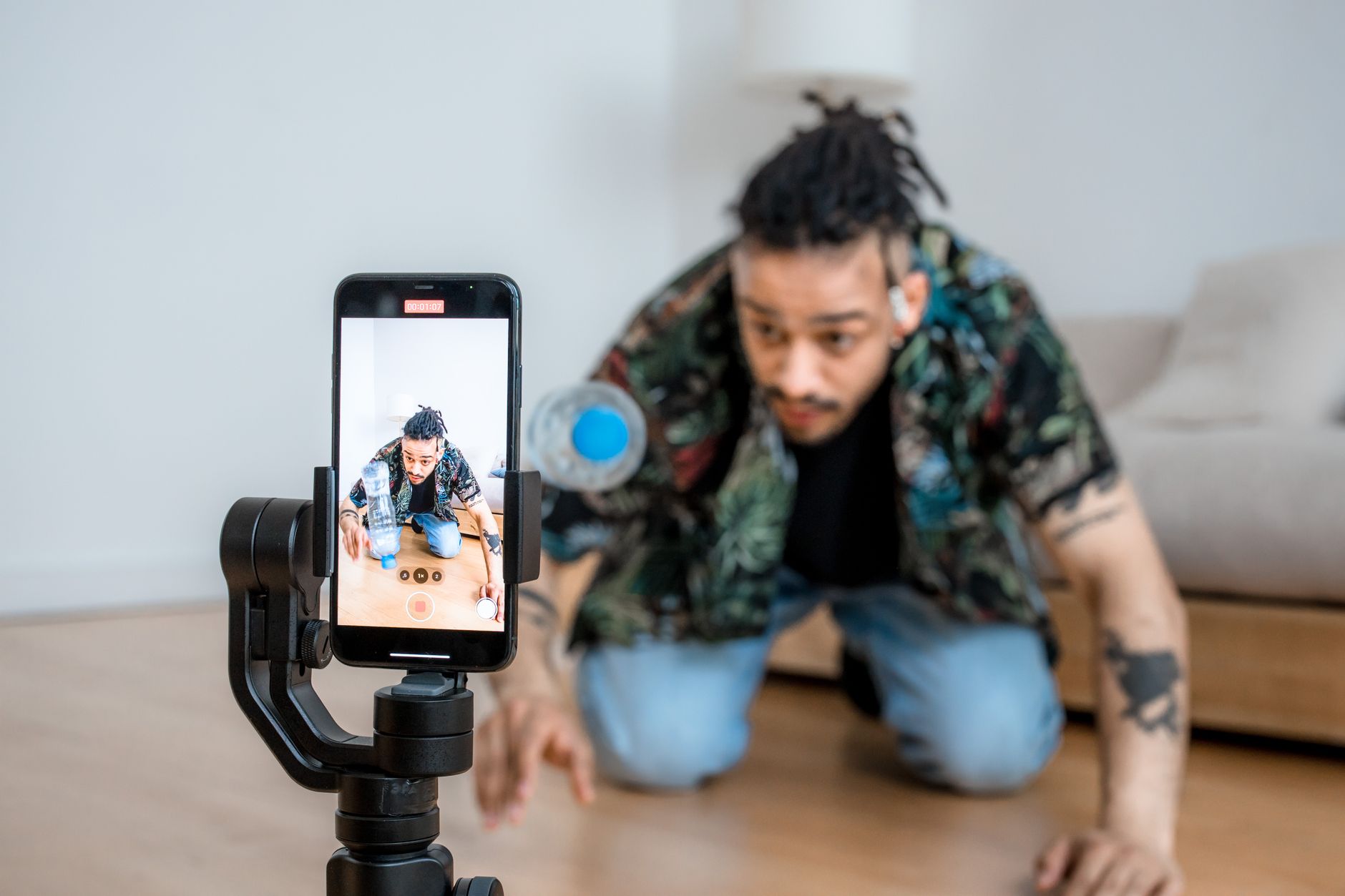 Man filming video content with a smartphone mounted on a gimbal stabilizer indoors
