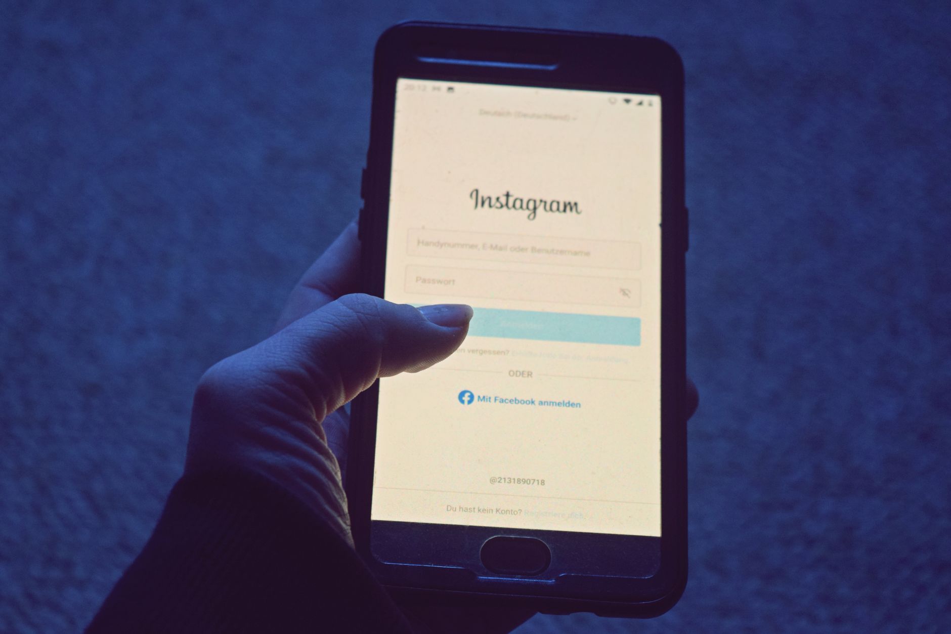 Close-up of a hand holding a smartphone open to the Instagram login screen.